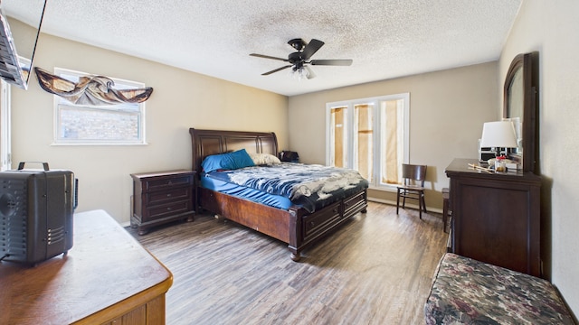 bedroom with a textured ceiling, wood finished floors, a ceiling fan, and baseboards