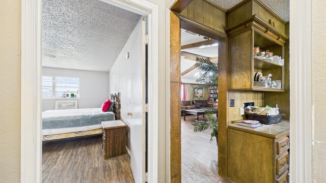 hall featuring a textured ceiling, a textured wall, and wood finished floors