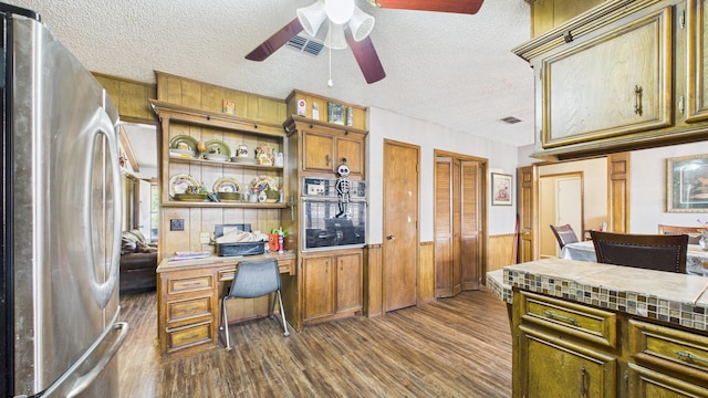 office area featuring a textured ceiling, wood walls, visible vents, dark wood-style flooring, and a ceiling fan