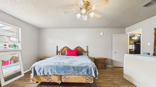 bedroom featuring a textured ceiling, a ceiling fan, wood finished floors, and visible vents