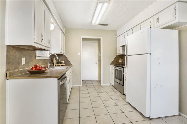 kitchen featuring sink, light tile patterned floors, appliances with stainless steel finishes, tasteful backsplash, and white cabinets