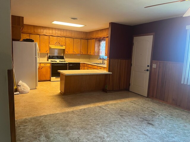 kitchen featuring white appliances, kitchen peninsula, sink, and wood walls