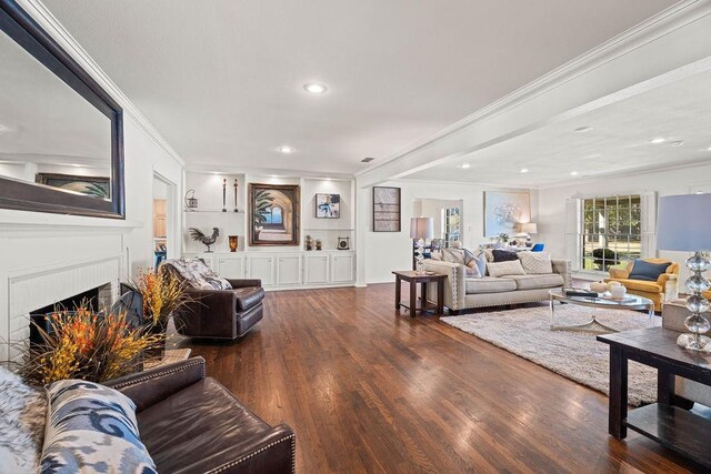 living room featuring dark wood-type flooring, ornamental molding, a fireplace, and built in features