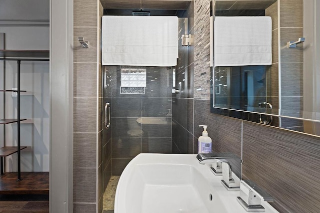 bathroom featuring tile walls, sink, and a shower with shower door