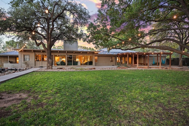 back house at dusk with a lawn