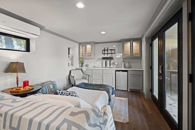 bedroom with an AC wall unit, refrigerator, dark hardwood / wood-style flooring, crown molding, and bar area