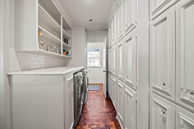 washroom featuring dark parquet flooring, washer and clothes dryer, and ornamental molding