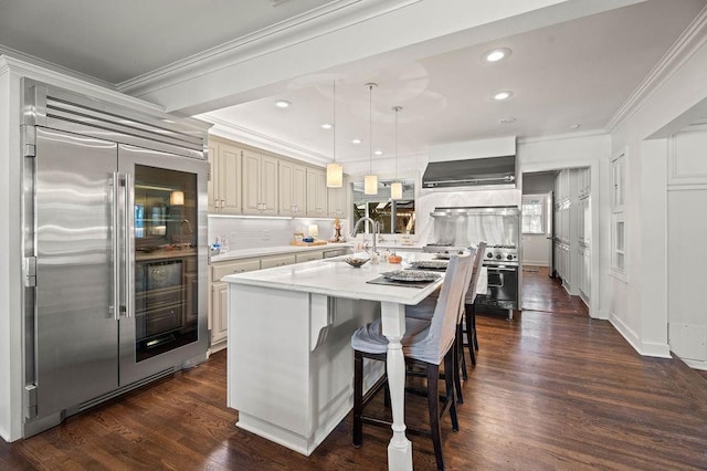 kitchen featuring sink, high quality appliances, ornamental molding, a kitchen island, and decorative light fixtures