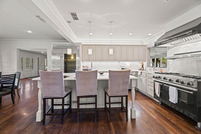 kitchen featuring a kitchen island, high quality appliances, decorative backsplash, hanging light fixtures, and exhaust hood