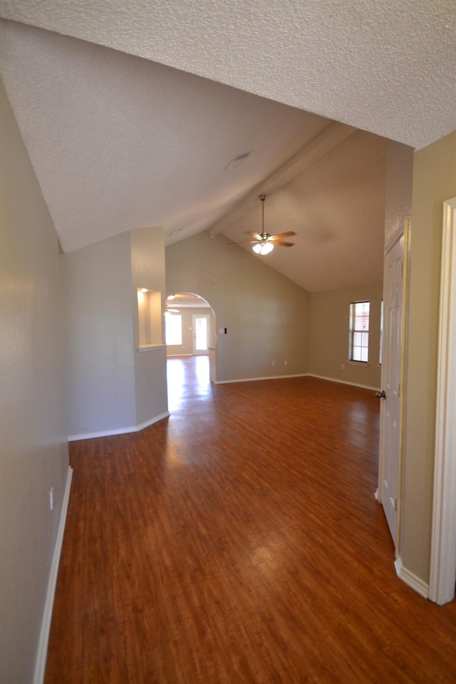 unfurnished room featuring ceiling fan, dark hardwood / wood-style flooring, lofted ceiling with beams, and a textured ceiling