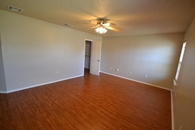 empty room with ceiling fan, dark wood-type flooring, and a textured ceiling