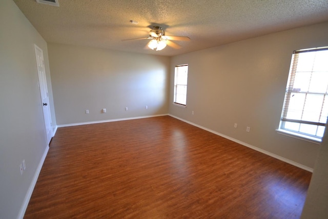 empty room featuring a textured ceiling, dark wood-type flooring, and ceiling fan