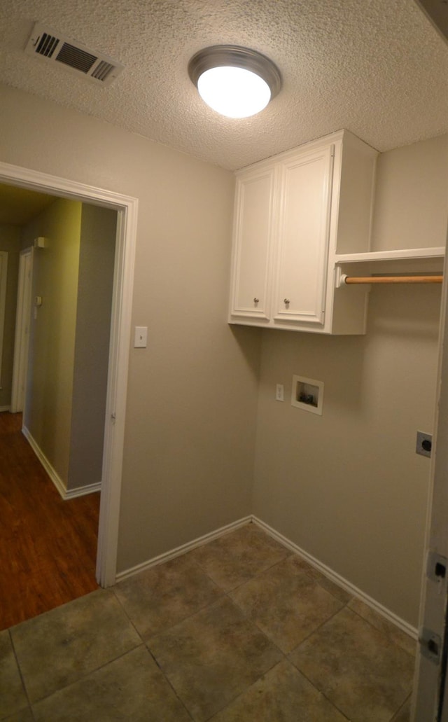 washroom with cabinets, washer hookup, dark tile patterned flooring, and a textured ceiling