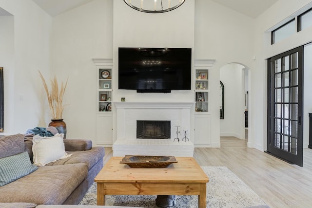 4309 136th St, Lubbock, TX 79423 - living room featuring arched walkways, high vaulted ceiling, wood finished floors, a brick fireplace, and baseboards