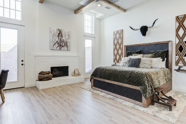 4309 136th St, Lubbock, TX 79423 - bedroom with a fireplace with raised hearth, beamed ceiling, wood finished floors, multiple windows, and access to exterior