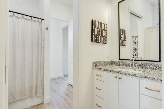 4309 136th St, Lubbock, TX 79423 - full bathroom with wood finished floors, a shower with curtain, vanity, and baseboards