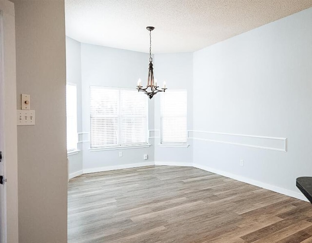 6916 Fulton Ave, Lubbock, TX 79424 - unfurnished dining area featuring a chandelier, wood finished floors, baseboards, and a textured ceiling