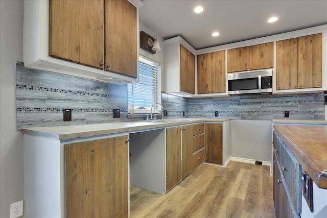 kitchen with sink, decorative backsplash, and light wood-type flooring