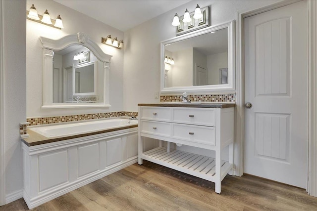 bathroom with tasteful backsplash, wood-type flooring, vanity, and a washtub