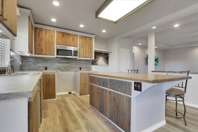 kitchen featuring a kitchen breakfast bar, a center island, sink, and light hardwood / wood-style flooring