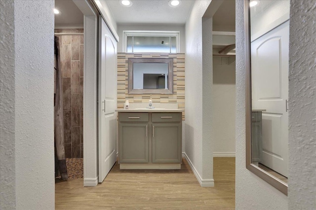 bathroom with walk in shower, vanity, and hardwood / wood-style floors