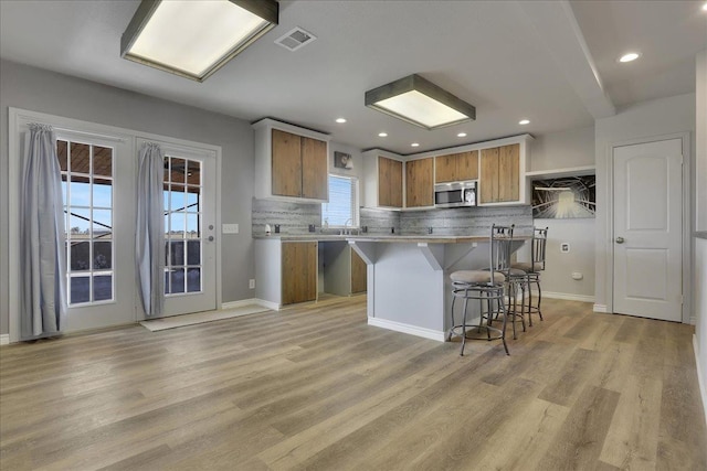 kitchen featuring tasteful backsplash, a kitchen island, a kitchen breakfast bar, and light hardwood / wood-style flooring