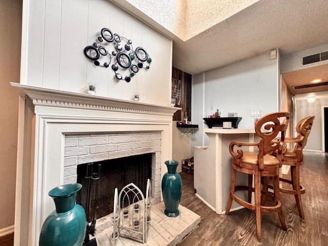 interior space featuring a brick fireplace, dark hardwood / wood-style floors, and a textured ceiling