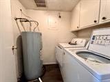 clothes washing area with water heater, washing machine and clothes dryer, and cabinets