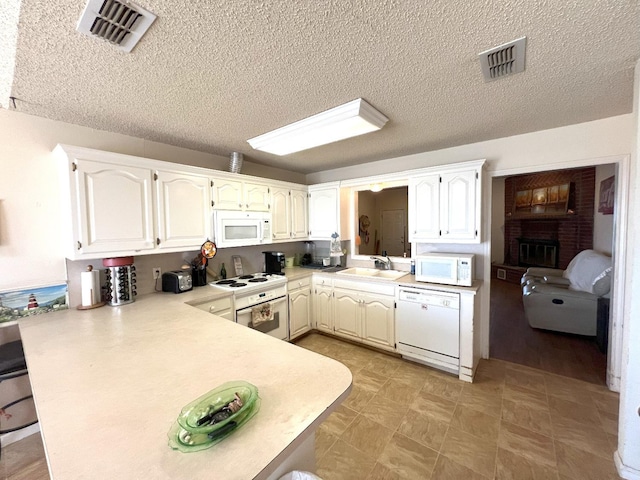 kitchen featuring white cabinetry, sink, white appliances, kitchen peninsula, and a textured ceiling