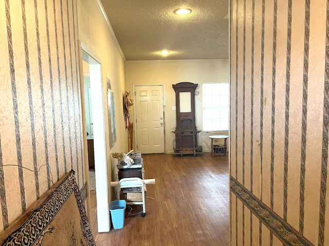 corridor with ornamental molding, wood-type flooring, and a textured ceiling