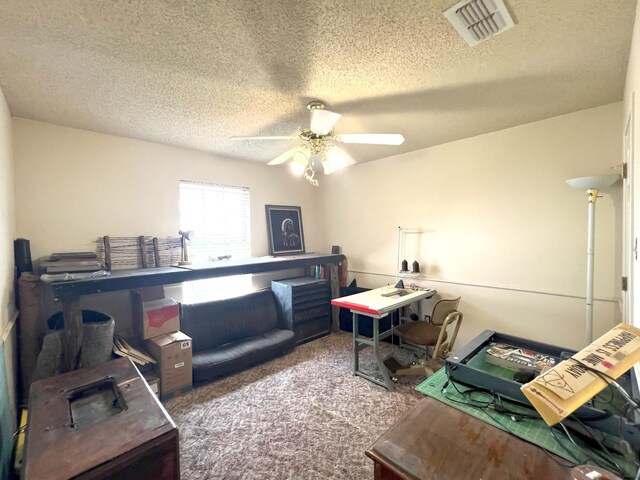 carpeted office space featuring ceiling fan and a textured ceiling