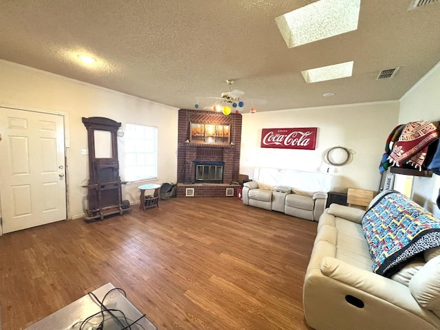 unfurnished living room with hardwood / wood-style flooring, ceiling fan, a skylight, a fireplace, and a textured ceiling