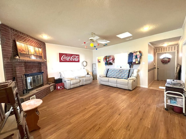 living room with hardwood / wood-style flooring, ceiling fan, a brick fireplace, and a textured ceiling