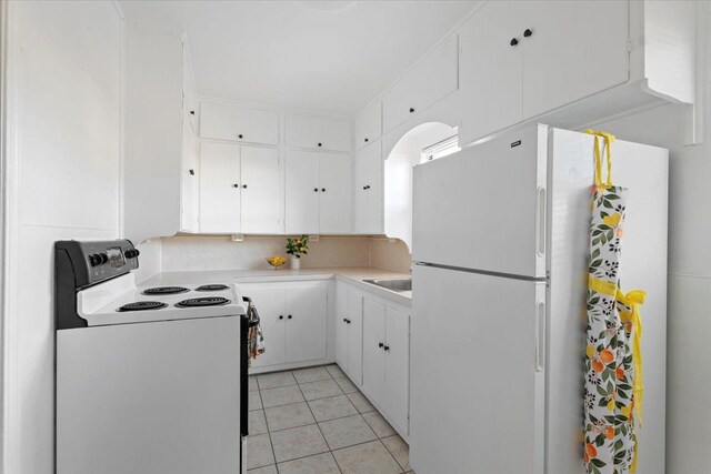 kitchen featuring electric range oven, white cabinetry, sink, white fridge, and light tile patterned floors