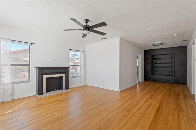 unfurnished living room with ceiling fan, a textured ceiling, and light hardwood / wood-style floors