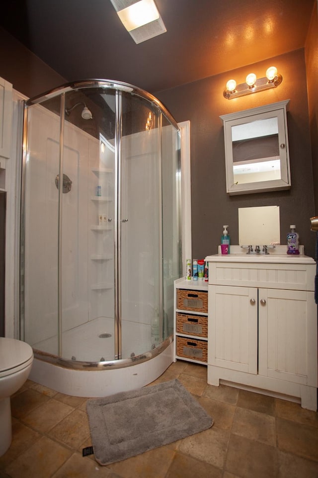 bathroom with vanity, a shower with shower door, and toilet