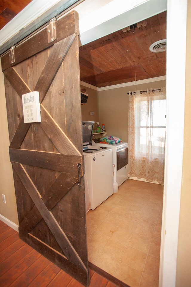 laundry area featuring ornamental molding, a barn door, washer and clothes dryer, and wooden ceiling