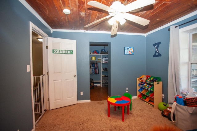 rec room with ornamental molding, wooden ceiling, ceiling fan, and carpet