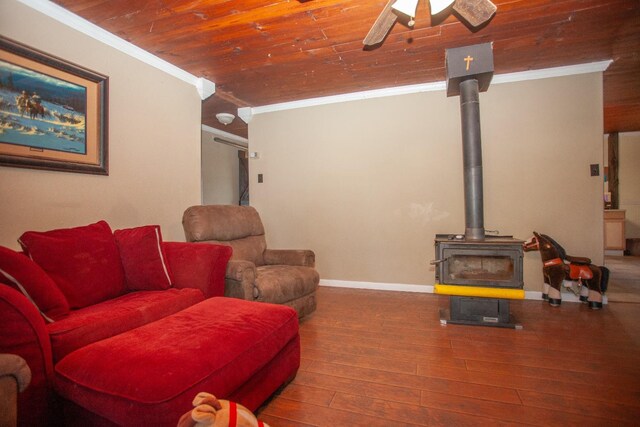 living room featuring crown molding, wood-type flooring, a wood stove, and wooden ceiling