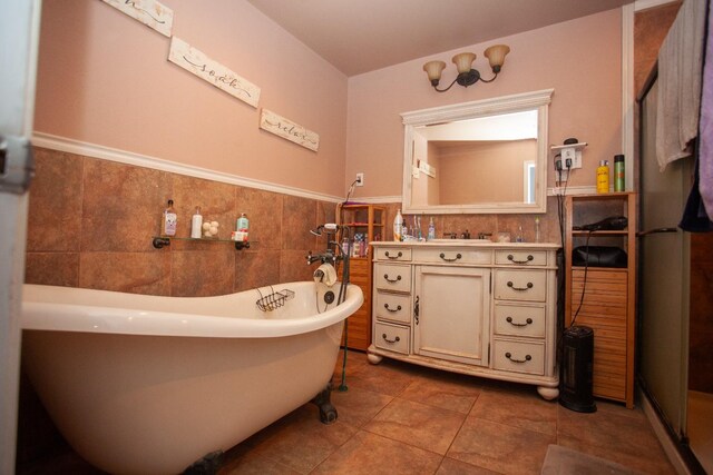 bathroom with tile patterned flooring, vanity, tile walls, and a tub to relax in