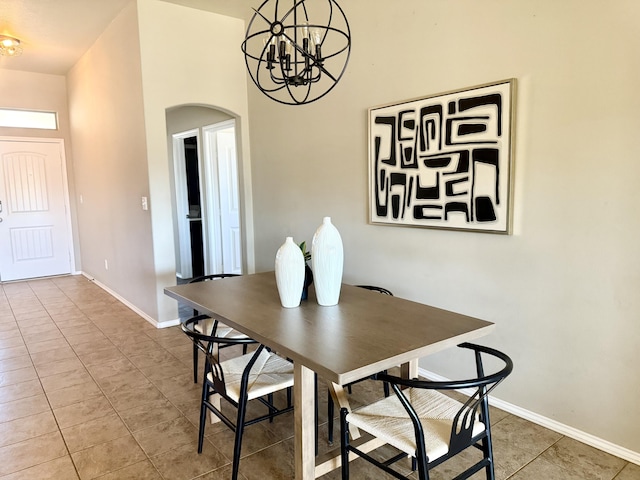 dining area featuring a chandelier, arched walkways, baseboards, and tile patterned floors