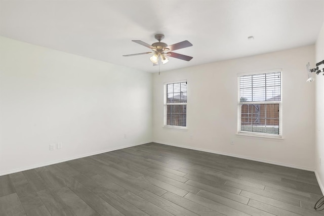 spare room featuring baseboards, dark wood finished floors, and a ceiling fan