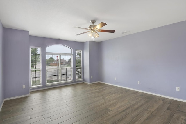 empty room featuring dark wood-style floors, baseboards, visible vents, and ceiling fan