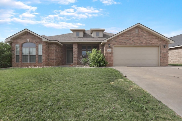 view of front of property with an attached garage, driveway, a front lawn, and brick siding