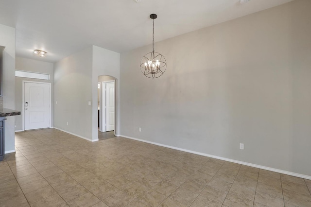 empty room featuring an inviting chandelier, baseboards, and arched walkways