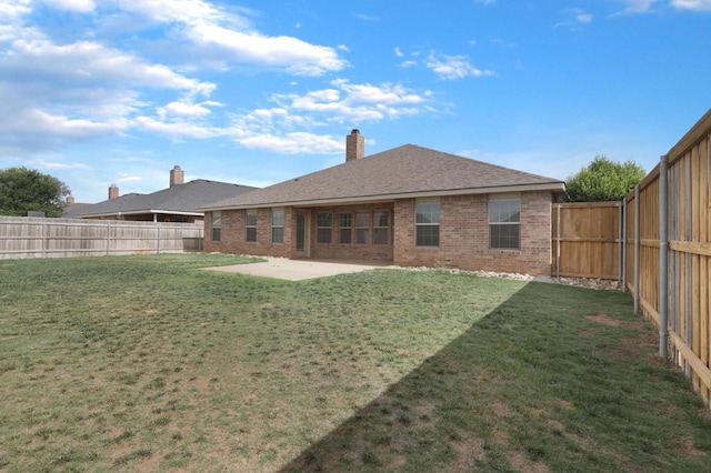 back of house featuring a yard, brick siding, a patio, and a fenced backyard