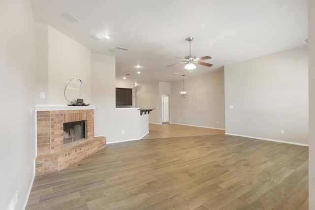 unfurnished living room featuring light wood-style flooring, a fireplace, visible vents, and a ceiling fan