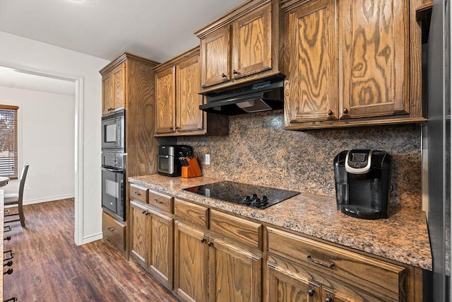 kitchen featuring light stone counters, dark hardwood / wood-style floors, backsplash, and black appliances