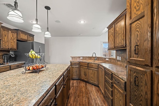 kitchen with sink, backsplash, stainless steel refrigerator with ice dispenser, dark hardwood / wood-style flooring, and decorative light fixtures