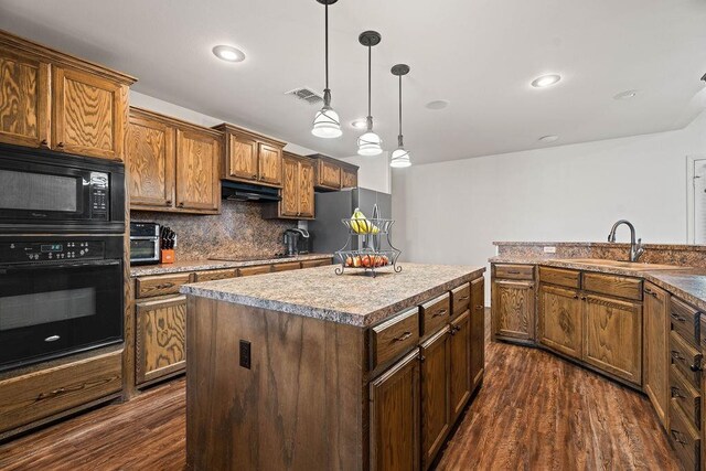 kitchen with pendant lighting, sink, dark wood-type flooring, black appliances, and a kitchen island